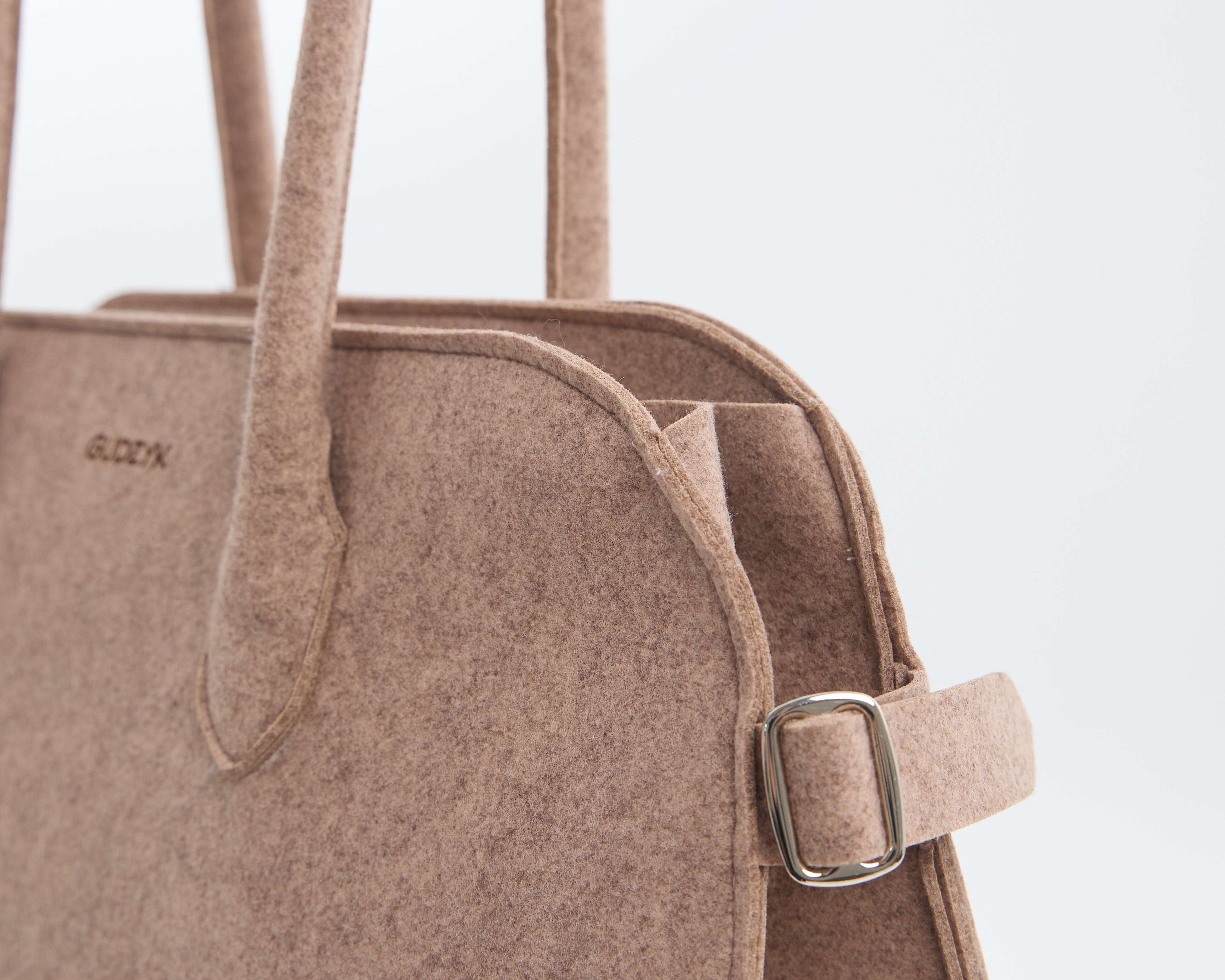 Close-up of a brown handbag with a strap on a light gray background